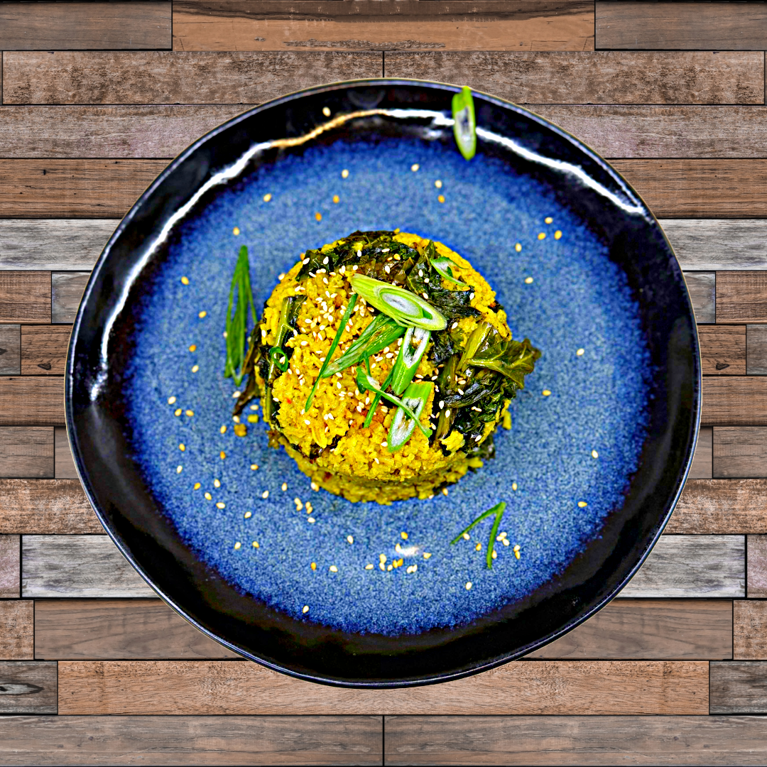 A round serving of orange-colored rice topped with sliced scallions on a blue plate and wooden table.