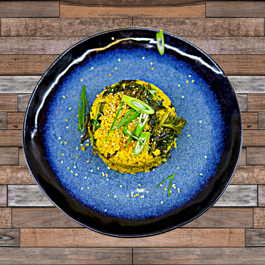 A round serving of orange-colored rice topped with sliced scallions on a blue plate and wooden table.